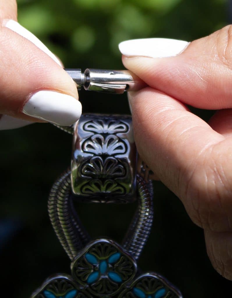 Close-up of hands fastening a decorative clasp on a bracelet.