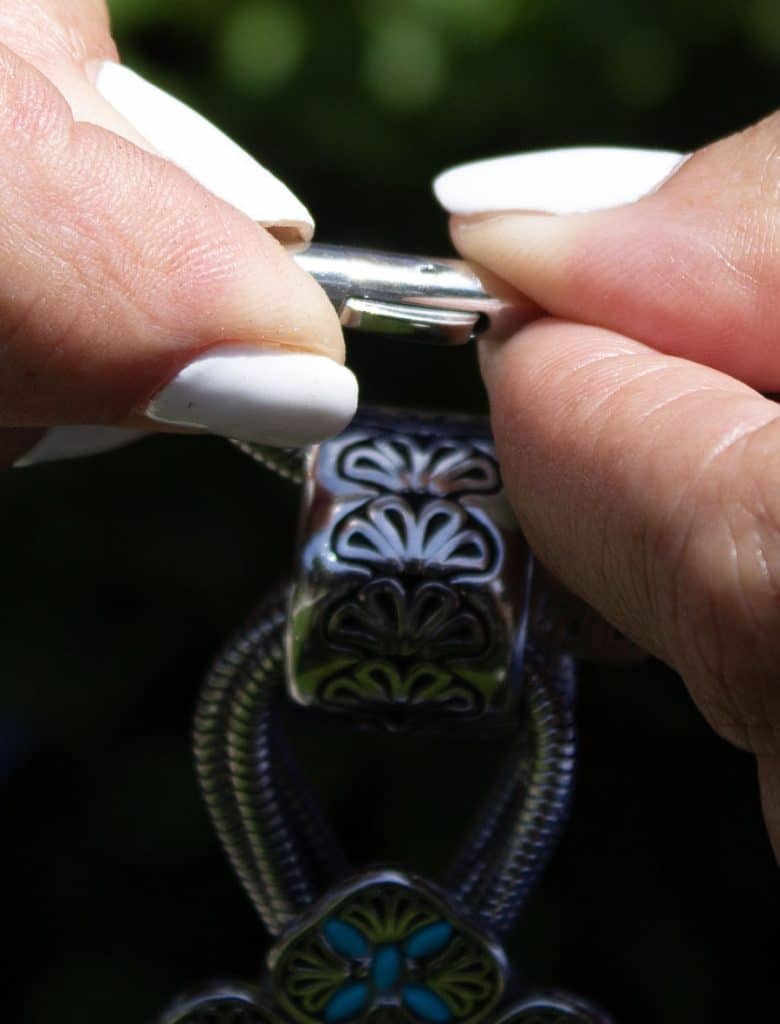 Close-up of hands painting detailed designs on a ring.