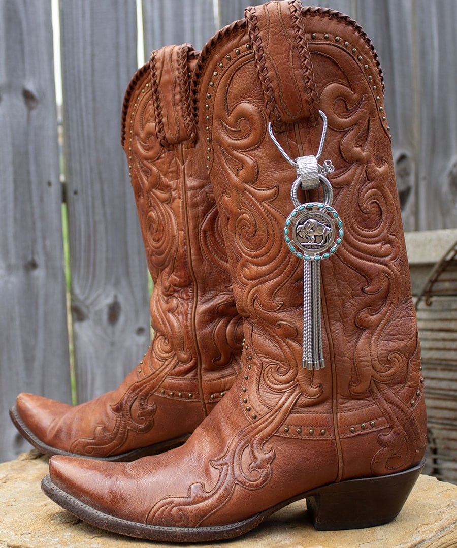 Pair of intricately designed brown leather cowboy boots with a keychain attached.