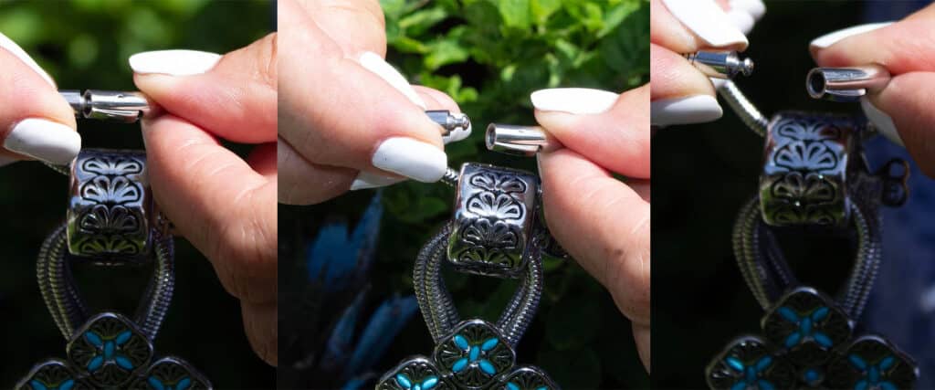 A person holding a detailed silver pendant with floral designs.